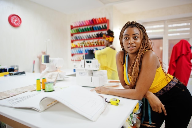 Dos modistas africanos cosen ropa en una máquina de coser en la oficina de sastre
