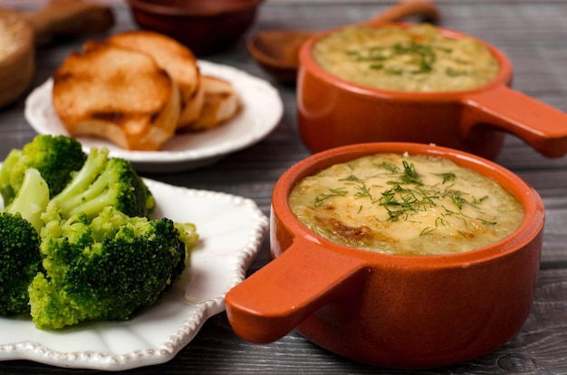 Dos moldes de cerámica sobre la mesa Sopa crema de brócoli y queso Brócoli en el plato