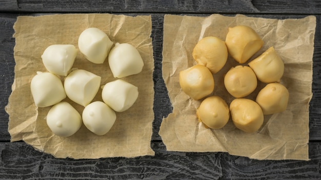 Dos montones de queso mozzarella recién hecho en un papel sobre la mesa de madera oscura.