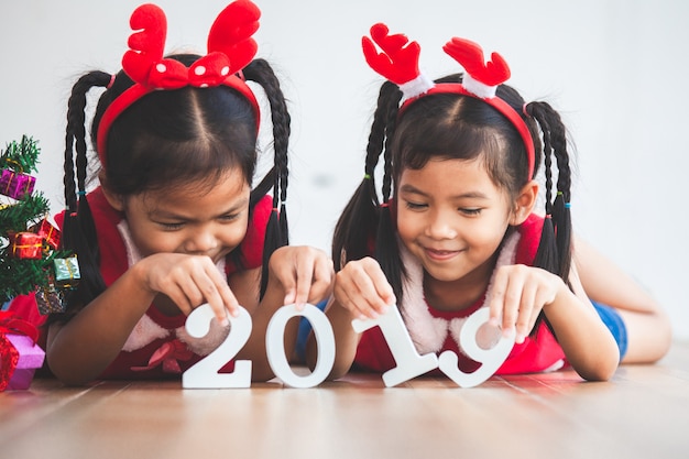 Dos muchachas asiáticas lindas del niño que llevan a cabo números 2019 para celebrar día de fiesta del Año Nuevo