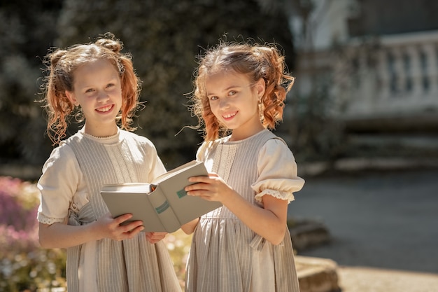 Dos muchachas de colegialas de primaria leen un libro en el patio de la academia.