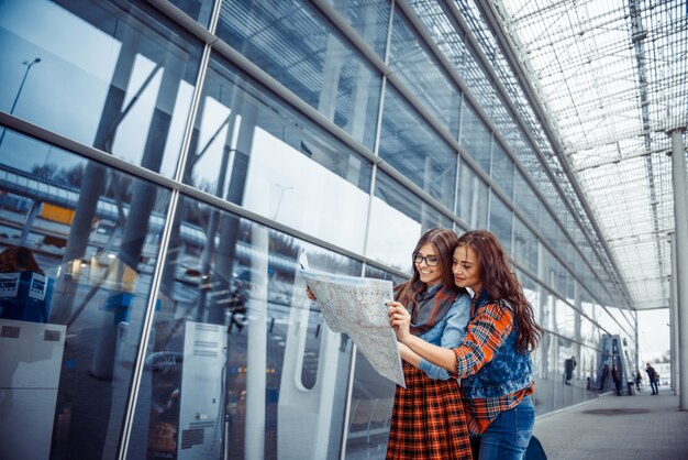 Dos muchachas hermosas jóvenes están estudiando y mirando el mapa.