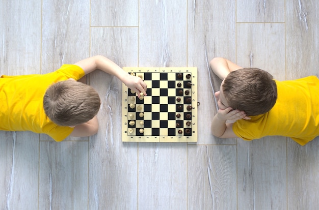 Dos muchachos caucásicos juegan al ajedrez en el suelo