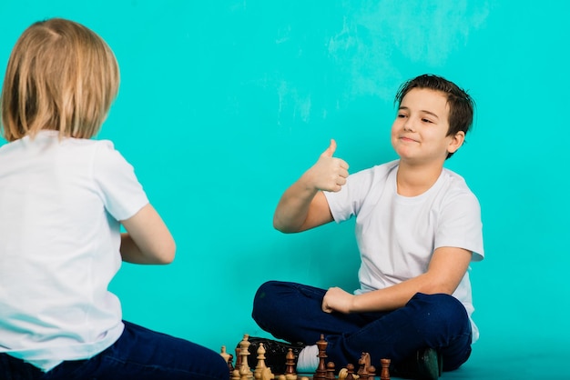 Dos muchachos serios jugando ajedrez estudio fondo azul.