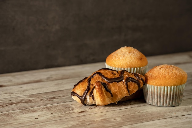 Dos muffins recién horneados y un croissant de chocolate en primer plano concepto de pastelería para el desayuno