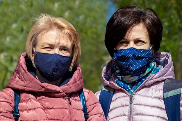 Dos mujeres adultas felices con máscaras protectoras