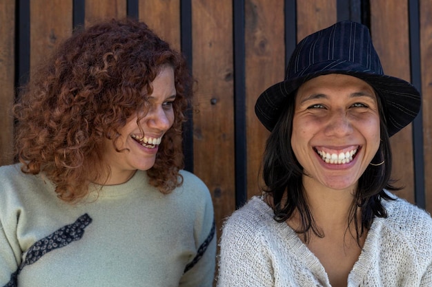 Foto dos mujeres adultas latinoamericanas con ojos verdes sonriendo divirtiéndose y pasando un buen rato juntas