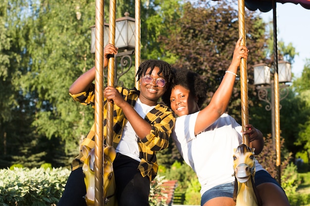 Dos mujeres afroamericanas felices en un parque en un paseo de diversión en el verano