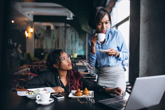 Dos mujeres afroamericanas con ordenador portátil y almuerzo