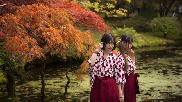 Foto dos mujeres asiáticas en kimonos de pie frente a un estanque