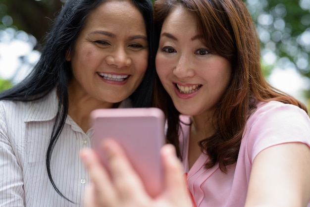 Dos mujeres asiáticas maduras juntas fuera del centro comercial en la ciudad de Bangkok