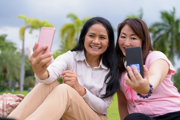 Dos mujeres asiáticas maduras juntas relajantes en el parque