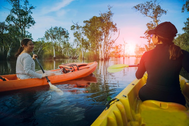 Dos mujeres asiáticas navegando en kayak de mar en la laguna de manglares