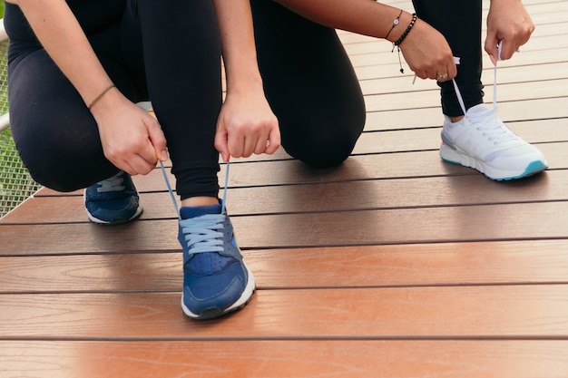 Foto dos mujeres ata los cordones de los zapatos y se prepara para trotar