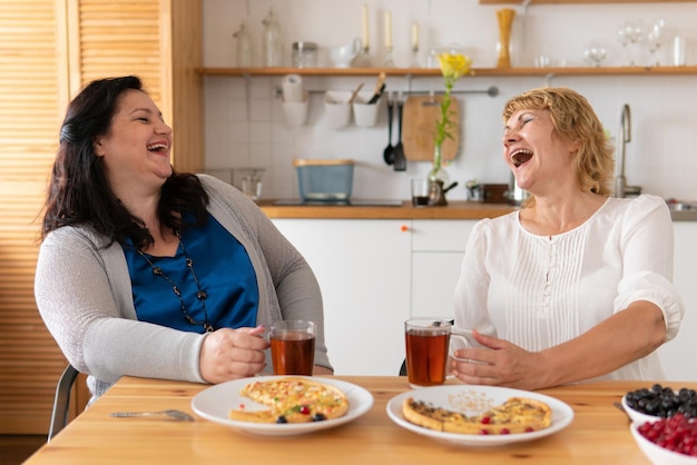 Dos mujeres bonitas están comiendo pizza en la habitación de la oficina.