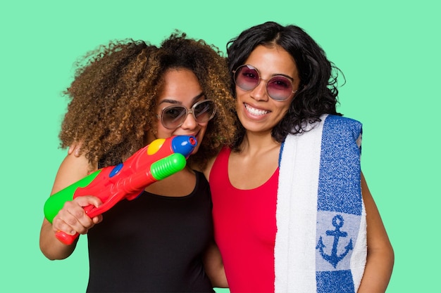 Dos mujeres, una con cabello afro y la otra latina, están listas para unas vacaciones en la playa en traje de baño