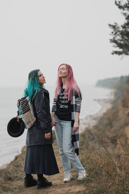 dos mujeres con cabello rosa y azul están tomados de la mano y sonriendo