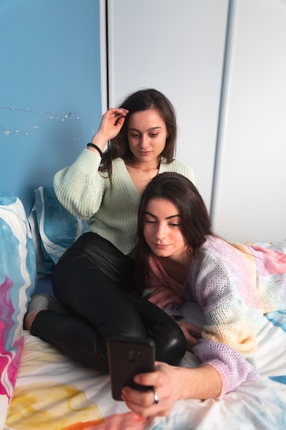 Foto dos mujeres en una cama con un teléfono inteligente