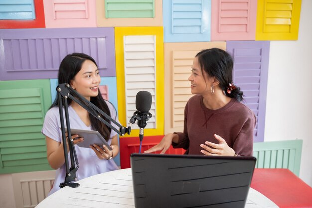 Dos mujeres charlando durante el podcast con micrófono y tableta