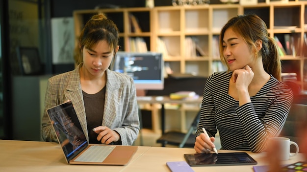 Dos mujeres desarrolladoras de TI trabajando juntas para desarrollar nuevo software en la oficina corporativa