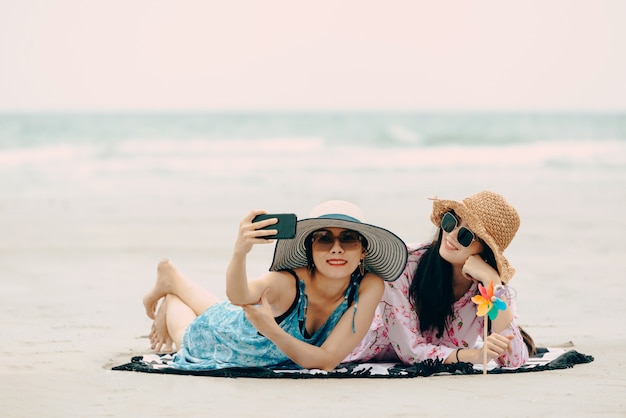 Dos mujeres disfrutando de la playa relajada y alegre en verano.