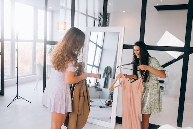 Foto dos mujeres eligen y prueban ropa en casa.