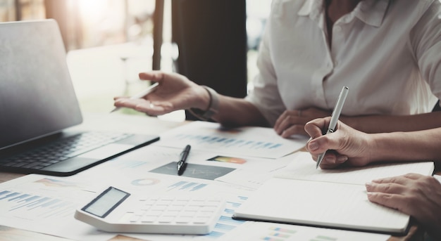 Dos mujeres empresarias están trabajando juntas para intercambiar ideas sobre cómo hacer crecer la empresa y hacer planes para controlar las finanzas de la empresa de acuerdo con el plan. Concepto financiero.