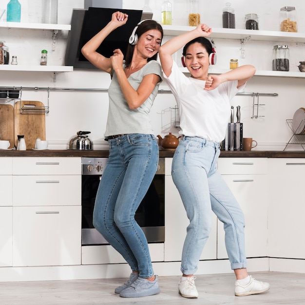 Foto dos mujeres escuchando música en auriculares y bailando