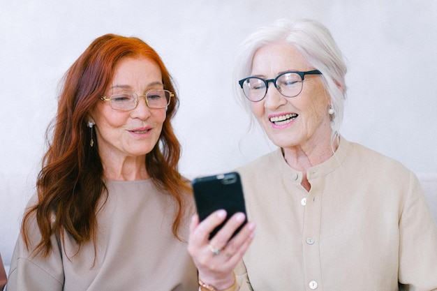 dos mujeres están mirando un teléfono que tiene las palabras cita vieja cita en él