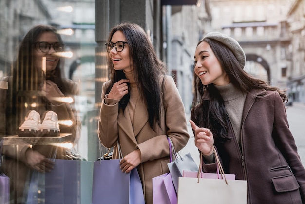 Dos mujeres felices comprando ventanas en un centro de la ciudad