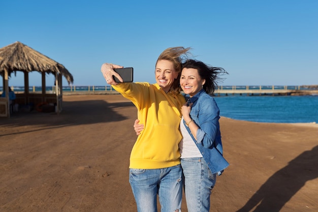 Dos mujeres felices maduras tomando una foto selfie juntas usando un teléfono inteligente