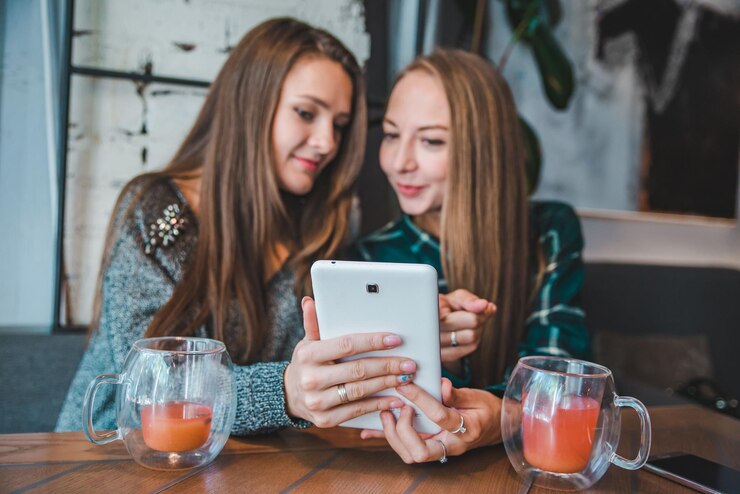 Foto dos mujeres hablando en el café bebiendo té mirando concepto de tableta