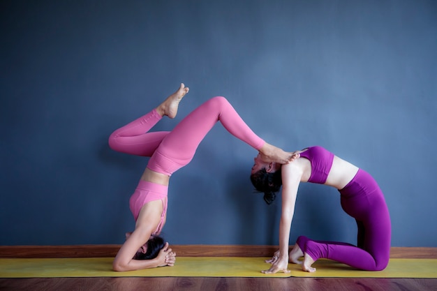 Dos mujeres haciendo pose de yoga en la sala de estar de casa