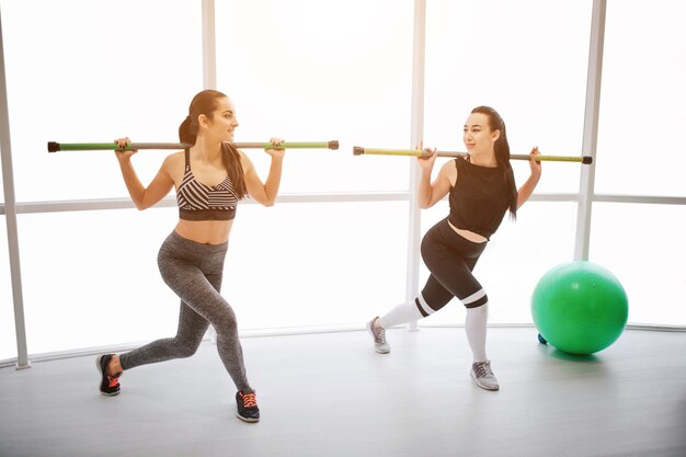 Dos mujeres jóvenes activas haciendo ejercicio en el gimnasio