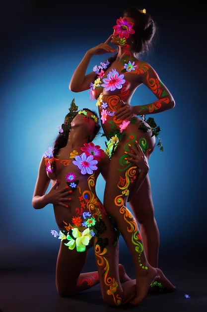 Dos mujeres jóvenes con arte corporal luminescente
