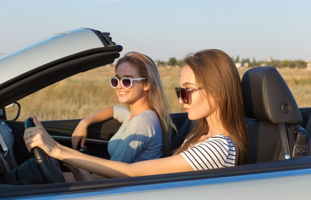 Dos mujeres jóvenes atractivas en un auto descapotable