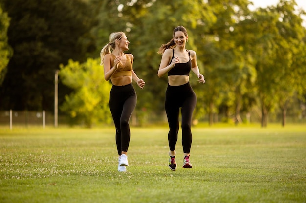 Dos mujeres jóvenes y bonitas corriendo en el parque