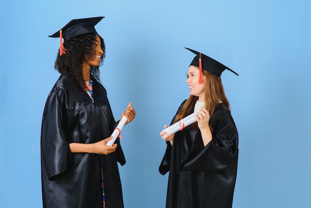 Dos mujeres jóvenes celebrando su graduación con diplomas