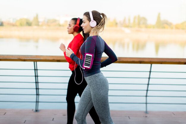 Dos mujeres jóvenes corriendo por el río en la mañana