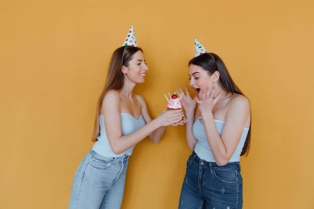 dos, mujeres jóvenes, en, cumpleaños, sombreros, celebrar, cumpleaños