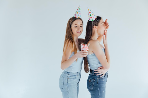 dos, mujeres jóvenes, en, cumpleaños, sombreros, celebrar, cumpleaños