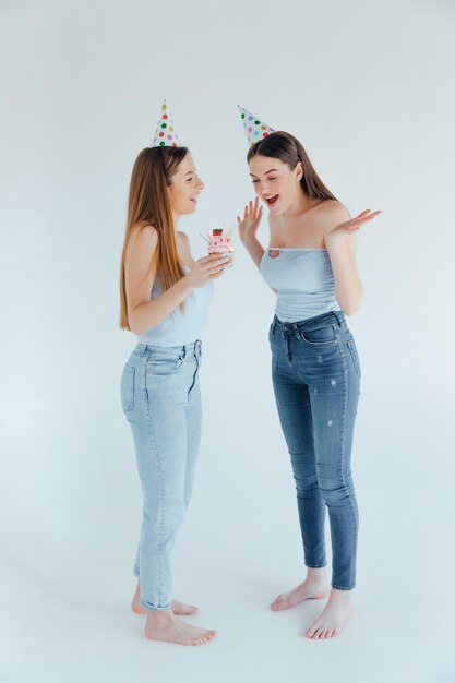 dos, mujeres jóvenes, en, cumpleaños, sombreros, celebrar, cumpleaños