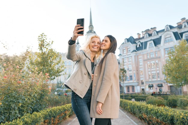 Dos mujeres jóvenes divirtiéndose, mirando el teléfono inteligente