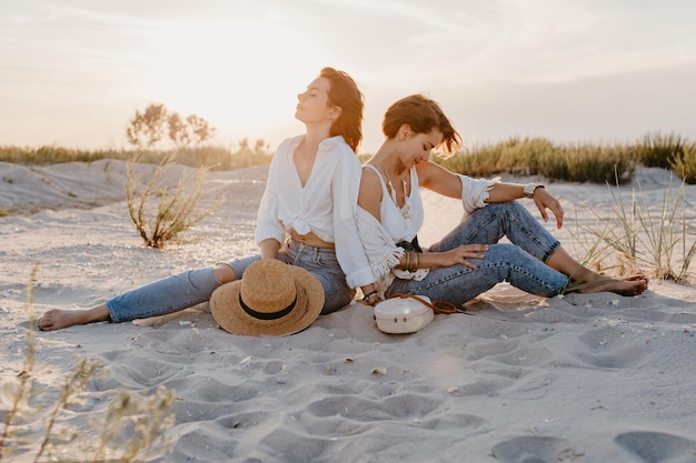 Dos mujeres jóvenes divirtiéndose en la playa al atardecer.