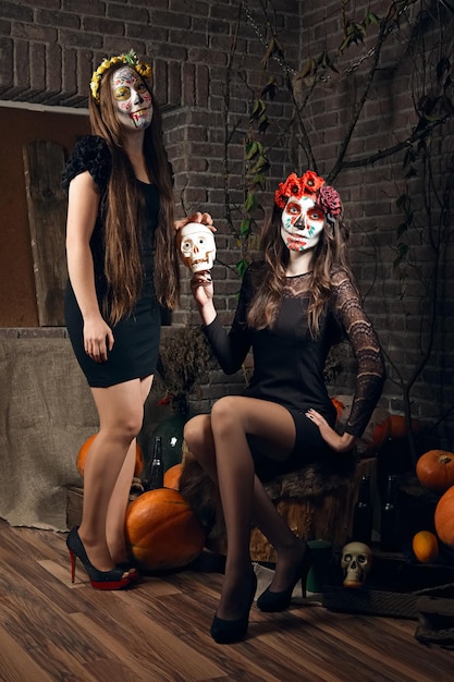 Dos mujeres jóvenes con maquillaje de calaveras de azúcar en la ubicación de Halloween