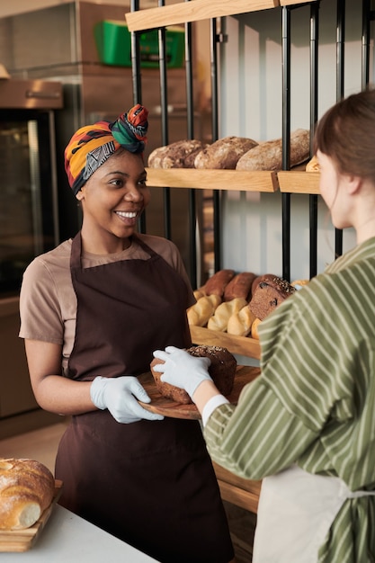 Dos mujeres jóvenes con pan trabajando en la panadería