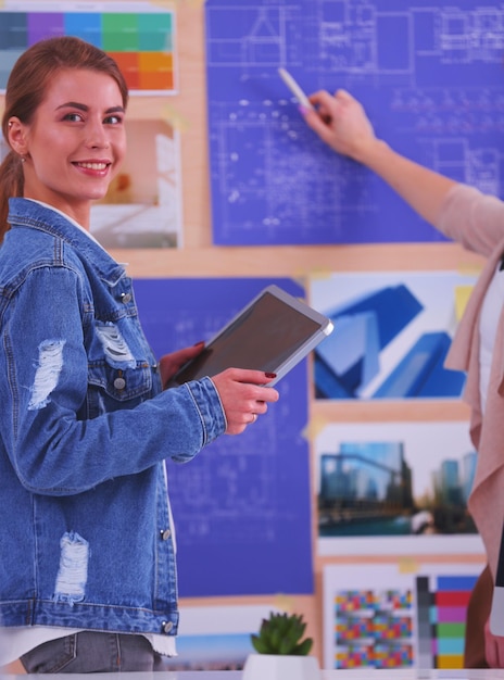 Dos mujeres jóvenes de pie cerca del escritorio con un plan de instrumentos y una computadora portátil