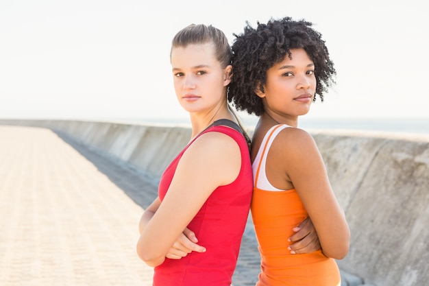 Dos mujeres jóvenes de pie espalda con espalda