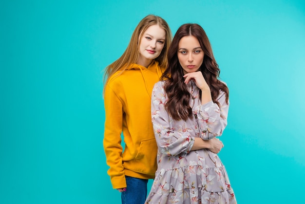 Dos mujeres jóvenes posando aislado sobre fondo azul turquesa brillante