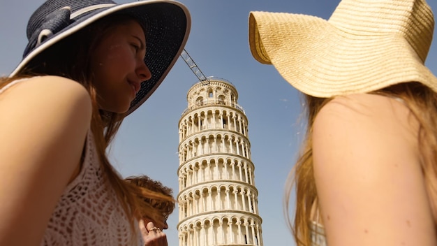 Dos, mujeres jóvenes, posición, debajo, el inclinar, torre, de, pisa, y, hablar